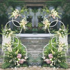 an arch decorated with flowers and greenery stands in front of the entrance to a garden