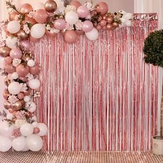 a pink and white party with balloons, streamers and flowers on the wall in front of it