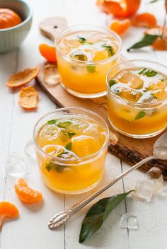 three glasses filled with orange juice and garnished with fresh mint on a cutting board