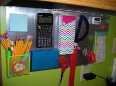 there is a cell phone, pencils, and other office supplies on the wall