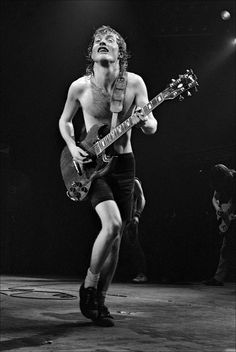 a shirtless man playing an electric guitar on stage