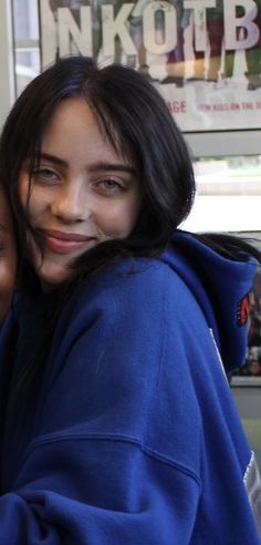 two girls are hugging each other in front of a window