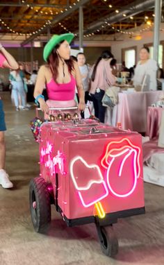 a woman in a pink tank top and green hat pushing a cart with candy on it