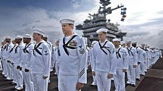 a group of men in white uniforms standing next to each other on top of a ship