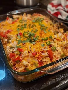 a casserole dish with chicken, rice and vegetables in it on the stove