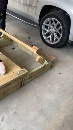 a car is parked in the garage next to a wooden structure with wheels on it