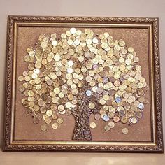 a tree made out of coins is on display in a gold frame with a brown background