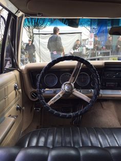the interior of an old car with leather upholstered seats and steering wheel controls
