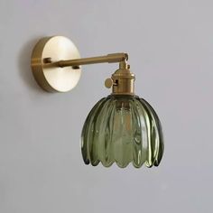 a green glass light hanging from the side of a wall