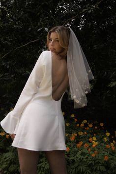 a woman in a short white dress with a veil on her head