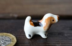 a small dog figurine sitting next to a penny on a table with a wooden surface