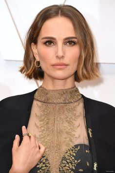 an image of a woman with short hair wearing a black suit and gold jewelry on the red carpet