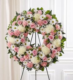 a pink and white wreath on a stand