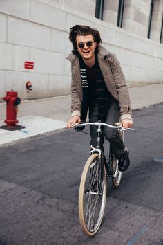 a man riding on the back of a bike down a street