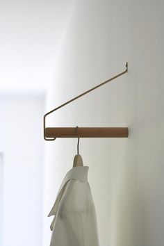 a white shirt hanging from a wooden hanger on a wall next to a door