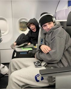 two people sitting on an airplane with headphones