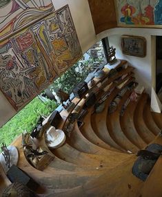 an aerial view of a wooden staircase in a building with paintings on the wall and below it