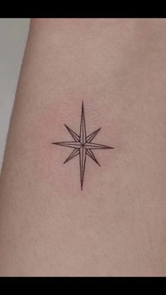 a small star tattoo on the back of a woman's thigh, with black ink