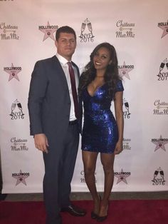 a man and woman standing next to each other in front of a red carpeted wall