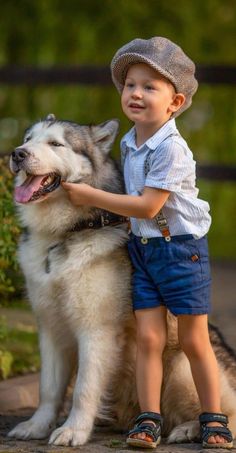 a little boy that is standing next to a dog