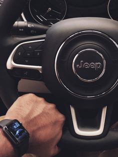 a man is holding the steering wheel of a jeep with his hand on the dashboard