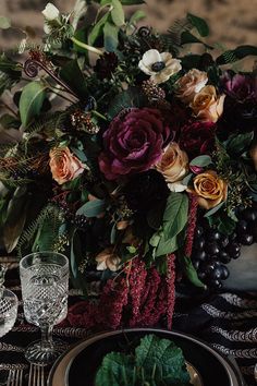 the table is set with flowers and fruit for an elegant fall wedding reception in burgundy tones