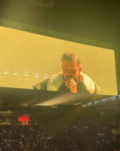 a man standing in front of a large screen at a concert