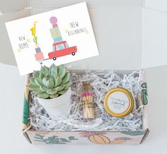 an open box with a card, potted plant and some other items inside it