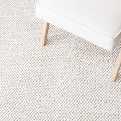 a white bench sitting on top of a carpeted floor next to a wooden chair