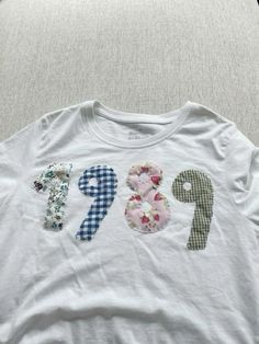 a white t - shirt with flowers and the word pep on it is laying on a bed