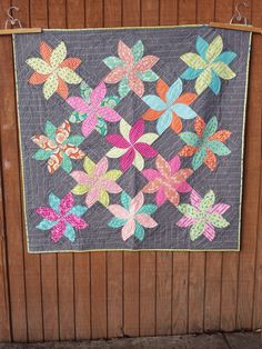 a quilt hanging on the side of a wooden fence