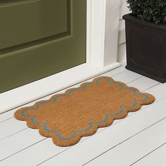 a brown door mat sitting on top of a wooden floor next to a potted plant