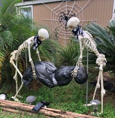 two fake skeletons are in the yard with trash bags