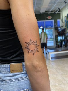 a woman's arm with a tattoo that has a sun on the middle of it