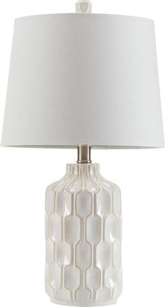 a white ceramic lamp with a white shade on it's base and a light bulb in the middle