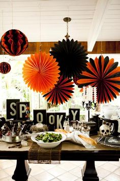 a table with paper fans hanging from it's ceiling and decorations on the wall