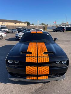the front end of a black and orange muscle car with an orange stripe on it