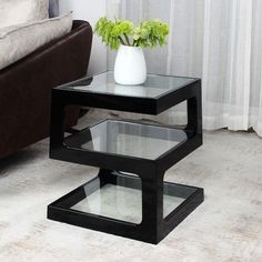 a black table with two glass tables on it and a brown couch in the background