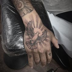 a person with a tattoo on their hand and a dove tattooed on the wrist is sitting in a chair