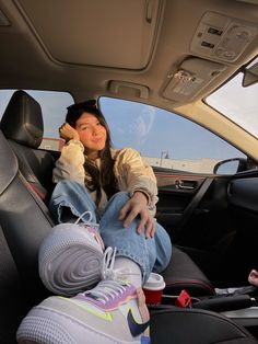 a woman sitting in the back seat of a car with her feet up and wearing sneakers