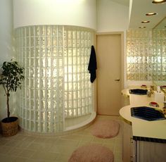 a bathroom with two sinks and a large round mirror on the wall above it is also a potted plant