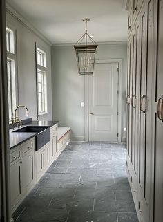 an empty kitchen with white cabinets and black counter tops in front of a light fixture hanging from the ceiling