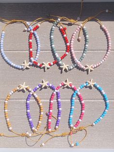 six bracelets with starfish charms on them sitting on a wooden table next to each other