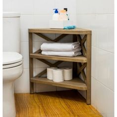a wooden shelf in the corner of a bathroom next to a toilet and paper towels