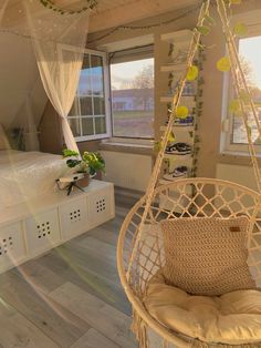 a bedroom with a bed, window and hanging chair in the middle of the room