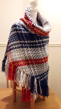 a white mannequin wearing a multicolored scarf on top of a wooden table