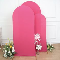 three pink stands with flowers in them on the floor