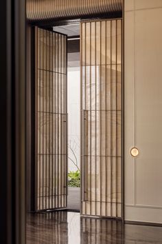 an open door leading into a room with wood flooring and vertical blinds on the walls