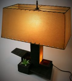 a lamp that is sitting on top of a table with a plant in the box underneath it