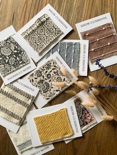 several cards with different patterns on them sitting on a wooden table next to dried flowers